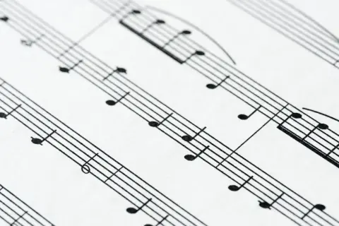 Zbliżenie na pięciolinię z nutami. Położenie nut na pięciolinii jest kluczowe do odczytania melodii.