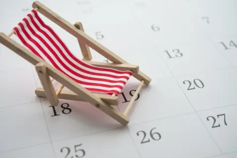Miniaturowa leżanka plażowa na kalendarzu z zaznaczonymi dniami.