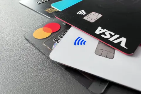 Nahaufnahme von Kreditkarten: eine schwarze Karte mit "VISA" und eine transparente Karte mit dem Mastercard-Logo.