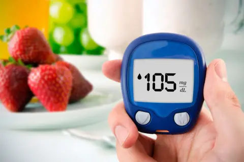 Glukometr pokazuje 105 mg/dL. Poziom cukru na czczo jest ważny dla zdrowia. W tle truskawki i napoje.