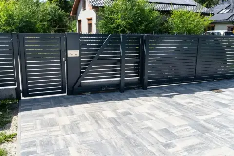 Nowoczesne, czarne ogrodzenie z automatyczną bramą. Czy ogrodzenie można odliczyć od podatku? Pytanie o inwestycję w bezpieczeństwo i estetykę posesji.