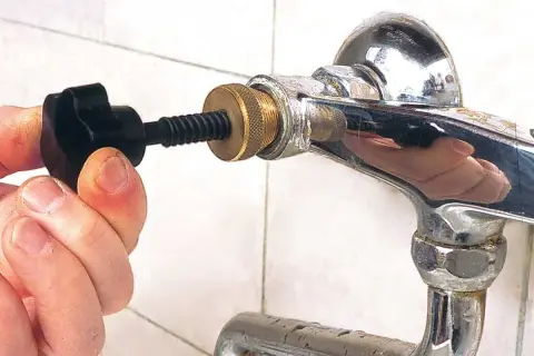Strumento per sbloccare un rubinetto bloccato dal calcare. La mano stringe la manopola nera per agire sul meccanismo.