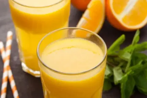 Dwa szklanki świeżego soku pomarańczowego, plasterki pomarańczy i listki mięty. Pyszny napój, który nie ma zbyt wielu pomarańcza kcal.