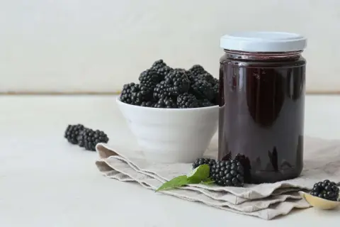 Frische Brombeeren und ein Glas selbstgemachtes Brombeergelee. So lässt sich das Gelee noch verfeinern.