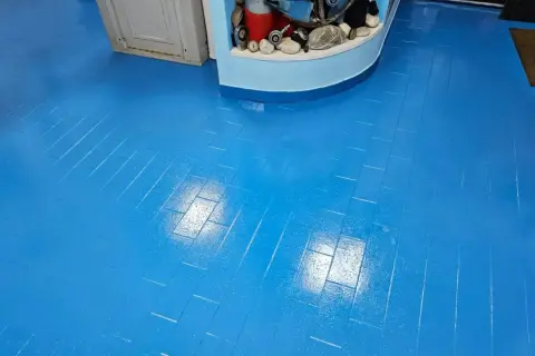 Pavimento blu brillante, effetto parquet, appena finito di lavorare la resina. Riflessi luminosi sulla superficie liscia.
