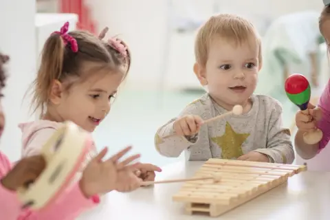 Kinder unter 3 Jahren musizieren fröhlich mit Xylophon und Maracas.