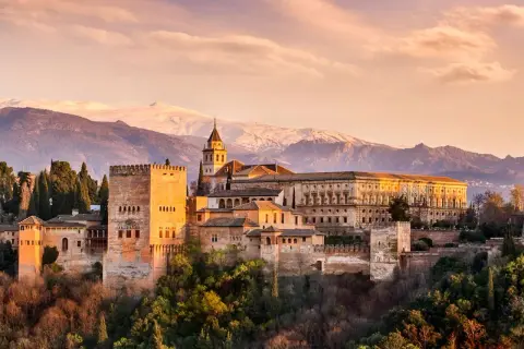Die Alhambra in Granada, ein Ort voller Geschichte und **Granada Geheimtipps**, thront vor schneebedeckten Bergen.