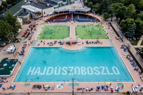 Hajdúszoboszló baseny cennik: aerial view of a large complex with multiple pools, including a vast blue pool with "HAJDÚSZOBOSZLÓ" written on the bottom.