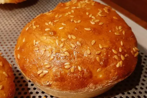 Un pain à burger maison doré et moelleux, parsemé de graines de sésame.