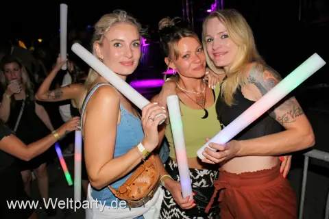 Drei Frauen mit leuchtenden Stäben auf einer Veranstaltung in Herrieden.