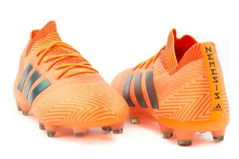 Pomarańczowe buty piłkarskie adidas Nemeziz 18.1 z czarnymi paskami i wzorem zygzak.