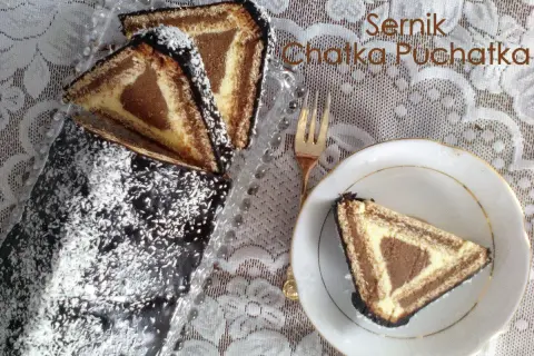 Ciasto "Chatka Puchatka" z polewą czekoladową i wiórkami kokosowymi. Na talerzyku kawałek ciasta w kształcie trójkąta.