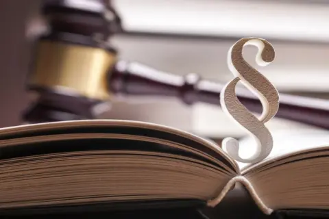 Otwarta księga prawa, paragraf i młotek sędziowski – symbole sprawiedliwości i arbitrażu.