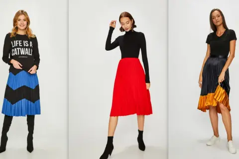Trzy kobiety prezentują modne stylizacje z plisowanymi spódnicami. Jedna w czarnej bluzie z napisem "LIFE IS A CATWALK" i spódnicy w niebiesko-czarne pasy. Druga w czarnym golfie i czerwonej spódnicy. Trzecia w czarnej bluzce i spódnicy w odcieniach gr...