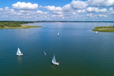 Segelboote auf dem Wasser in Masuren, Polen. Ein sonniger Tag mit Wolken, ideal zum Segeln.