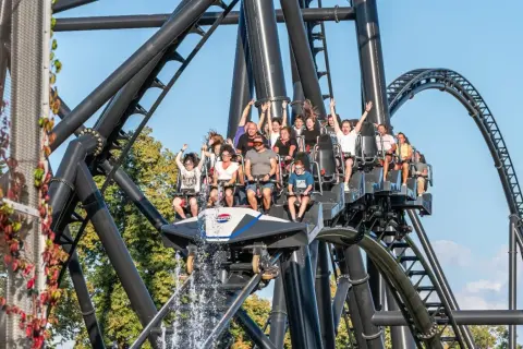 Ludzie na kolejce górskiej w Energylandii, z wodą tryskającą z przodu wagonika. Taka przejażdżka to świetny pomysł na wykorzystanie biletu rocznego Energylandia!