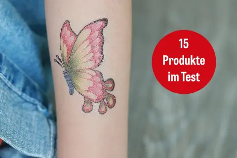 Ein buntes Schmetterlings-Tattoo mit 16 Jahren auf dem Arm. Daneben ein roter Kreis mit der Aufschrift "15 Produkte im Test".