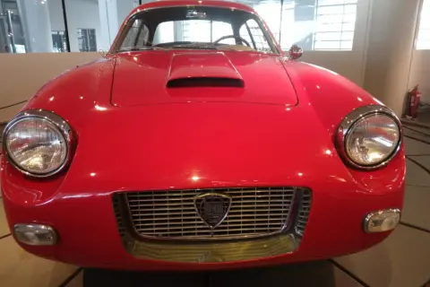 Vorderansicht eines roten italienischen Oldtimers mit Lancia-Logo im Kühlergrill.