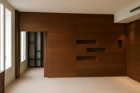 Parete moderna con finitura in impiallacciato rovere, nicchie integrate e un'apertura su una libreria a giorno.