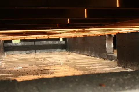 Fundament pod słupy drewniane, z bloczków betonowych, z wilgotną ziemią i drewnianym stropem.