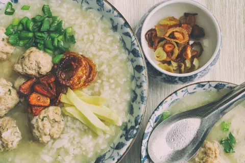 Pyszny congee z klopsikami, szczypiorkiem i chrupiącą cebulką. Idealne na rozgrzewający posiłek.