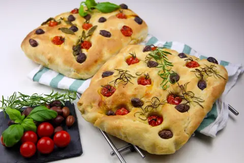 Två gyllene focaccia med tomater, oliver och rosmarin. Ett perfekt focaccia recept från Zeina som ser ljuvligt ut!