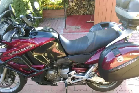 Czerwony motocykl Honda Varadero 1000 z kuframi, zaparkowany na podjeździe.