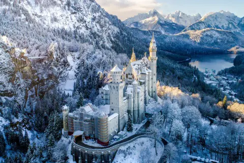 Schloss Neuschwanstein im winterlichen Glanz, ein märchenhafter Ort für einen Urlaub im Dezember. Schnee bedeckt die Berge und Bäume.
