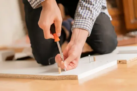 Man at work, using a screwdriver to unir tablero.