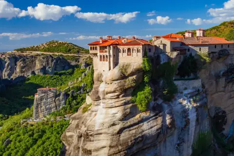 Meteora Kloster, ein atemberaubendes Bauwerk auf Felsen, thront majestätisch über einer grünen Schlucht.