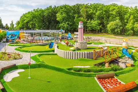 Mini golf w Rewalu to świetna zabawa! Wesołe dekoracje, w tym latarnia morska i rekin, zachęcają do gry.