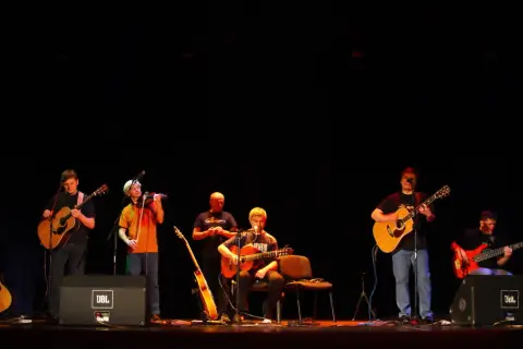 Zespół gra na gitarach i skrzypcach. W tle słychać **stare dobre małżeństwo utwory**.