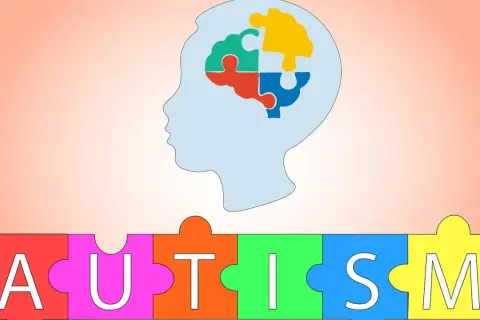 Sylwetka głowy z mózgiem z puzzli, poniżej napis AUTISM ułożony z kolorowych puzzli. Symbolizuje zespół Aspergera.