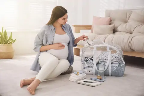 Przyszła mama przygotowuje torbę do porodu, układając maleńkie buciki na wierzchu.