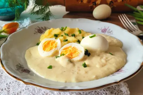 Jajka w sosie chrzanowym z ziemniakami, udekorowane szczypiorkiem. Pyszne danie, które rozpływa się w ustach.