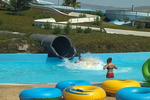 ¡Diversión en el parque Mario Park! Niños se deslizan por toboganes acuáticos y chapotean en la piscina con flotadores coloridos.