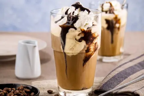 Ein erfrischender Eiskaffee mit Vanilleeis, garniert mit Sahne und Schokoladensauce. Perfekt für einen warmen Tag.