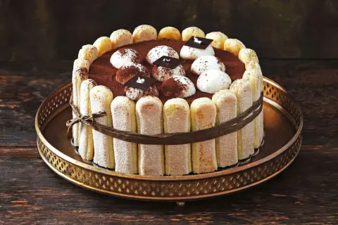 Ein köstliches, original italienisches Tiramisu-Torte, umrandet von Löffelbiskuits und verziert mit Kakao und Schokolade.