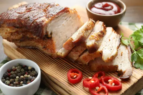 Soczysty boczek pieczony w piekarniku, pokrojony w plastry, z dodatkiem pieprzu, chili i sosu. Idealny przepis na to, jak upiec boczek surowy w piekarniku.