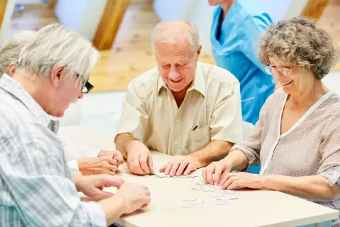 Des résidents d'un EHPAD participent à un atelier cognitif, assemblant un puzzle.