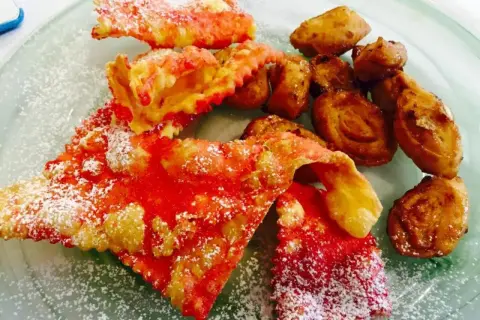 Dolci di carnevale marchigiani: chiacchiere rosse e frittelle dorate, cosparse di zucchero a velo, un piacere per gli occhi e il palato.