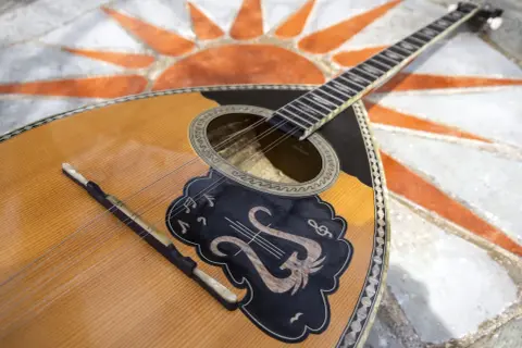 Piękny grecki instrument muzyczny, bouzouki, leży na mozaice w kształcie słońca.