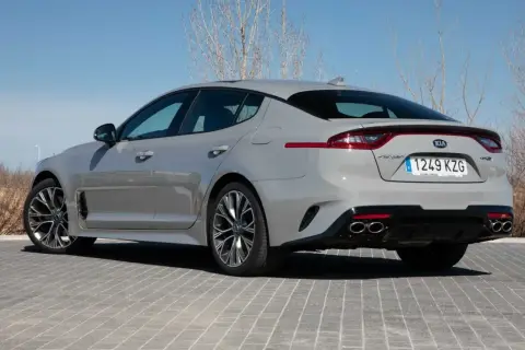 Kia Stinger GT CV gris, visto desde atrás, aparcado sobre adoquines grises.