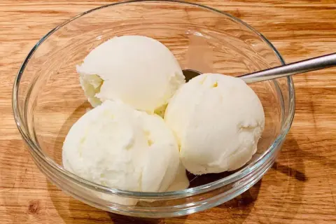 Schüssel mit drei Kugeln Milcheis ohne Sahne, perfekt zum milcheis ohne sahne selber machen. Löffel liegt daneben.