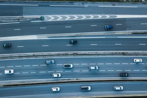 Widok z góry na autostradę, gdzie samochody wykonują manewry **wymijania** i **omijania** przeszkód, tworząc dynamiczny obraz ruchu drogowego.