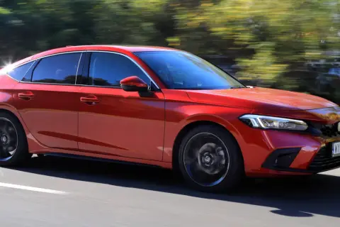 Czerwony Honda Civic 11 na drodze, z rozmytym tłem drzew.