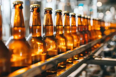 Szklane butelki piwa Tyskie na linii produkcyjnej. Różne rodzaje butelek czekają na napełnienie.