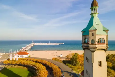Widok na latarnię morską w Sopocie, plażę i molo w jesienny, słoneczny dzień.