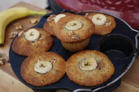 Frisch gebackene Bananen Nuss Muffins, garniert mit Bananenscheiben und Walnüssen, liegen in einer Muffinform.