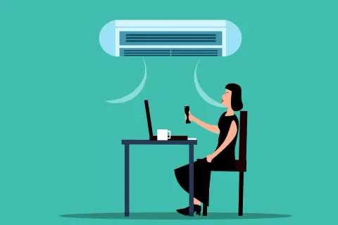 Une femme ajuste la climatisation pour une température idéale au bureau, profitant d'un environnement de travail confortable.